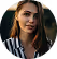 Young woman with long straight brown hair wearing a striped black and white shirt against a gray background.